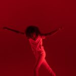photography of woman dancing near red background