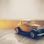 selective focus photography of classic brown coupe die-cast model on gray ground